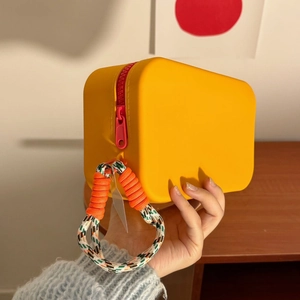 Detail of a yellow silicone makeup bag with pink zipper and braided rope handle