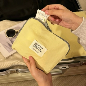 Close-up of waterproof yellow travel organizer bag with grey zipper and woven label