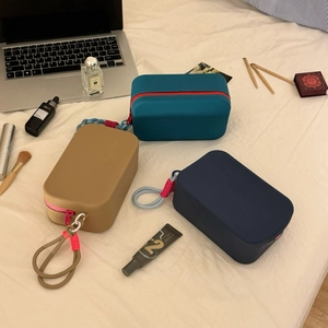 Flat lay of colorful silicone cosmetic bags with zippers and lanyards on white linens