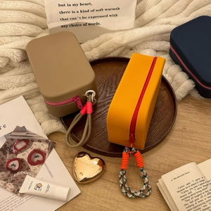 Silicone toiletry bags with braided ropes and contrast zippers on a wooden tray