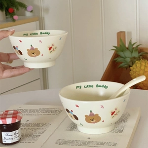 Detail of cream ceramic bowls set with cute bear and dog prints and matching spoons