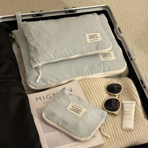 Close-up of three light blue travel organizer bags neatly packed in a modern suitcase