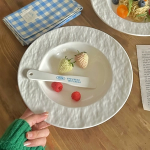 Minimalist white ceramic pasta plate with rock texture edge and matching butter knife