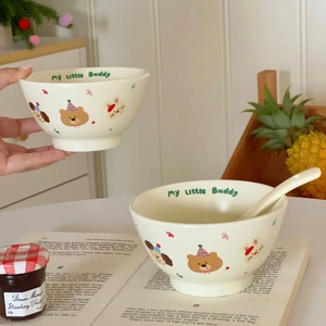 Detailed close-up of cream ceramic bowl set with cute animal illustrations and green text