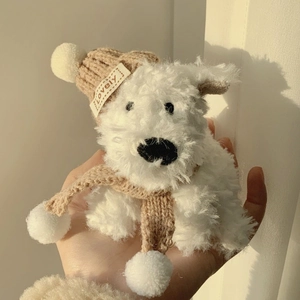 Close-up of white plush dog toy wearing a brown knit hat and scarf with Lovely label