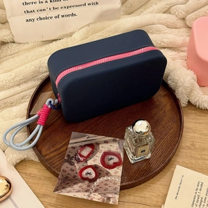 Detail of blue silicone makeup bag with pink zipper on a wooden tray with a cozy backdrop