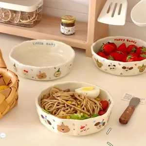 Close-up of cute matte cream ceramic bowl with wavy petal edges and cartoon animal patterns