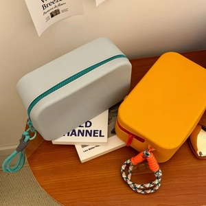 Detail view of colorful silicone makeup bags on a wooden surface with woven zipper pulls