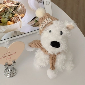 Detailed shot of white plush Westie dog wearing a brown knit hat and lovely scarf
