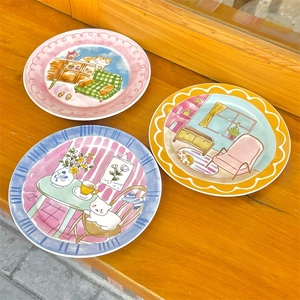 Detail of three ceramic plates featuring cute hand-painted cat illustrations for breakfast