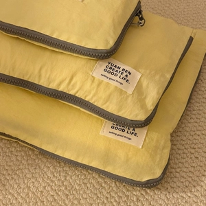 Close-up of bright yellow waterproof travel organizer bag with gray zipper and logo