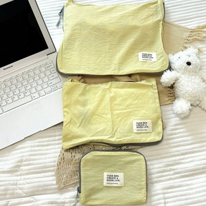 Detail view of a three-piece yellow nylon travel organizer set with zipper and brand label