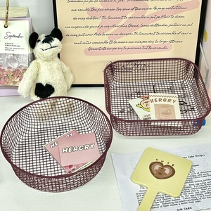 Close-up of deep red wire mesh storage baskets in round and rectangular shapes for desk