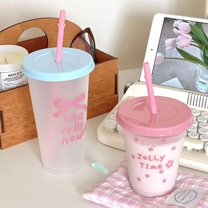 Detail van crèmekleurige plastic bekers met rietje en prints van strikken en sterren