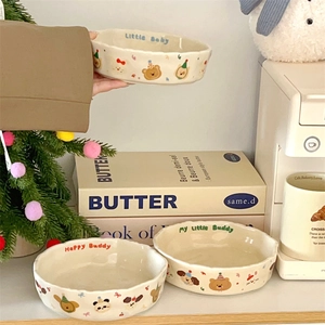 Detail of ceramic deep plates with hand-painted bear patterns and matte cream glaze