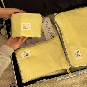 Travel organizer bags in lemon yellow color inside a silver suitcase with magazine decor