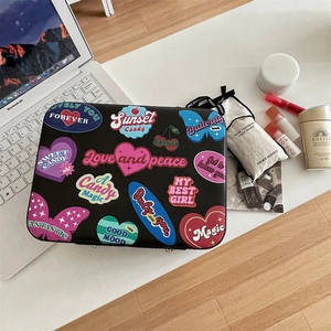 Macro view of a 13-14 inch black laptop sleeve with colorful pop art stickers on a desk
