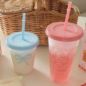Detail van roze en blauwe matte herbruikbare bekers met rietjes in een picknickmand