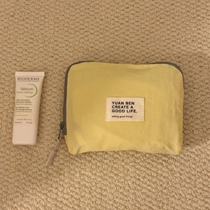 Close-up of yellow waterproof travel organizer bag with a compact 30ml tube for size reference