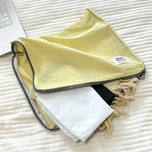 Detail of yellow nylon travel organizer bag showing large capacity for clothes and blankets