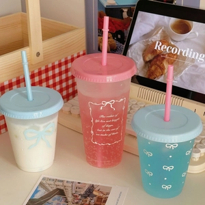 Close-up of pastel matte cold cups with straws featuring bow patterns and motivational quotes