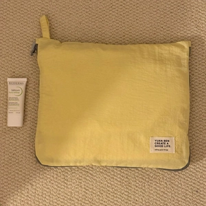 Detail of a thin yellow waterproof travel organizer with a zipper and side handle strap