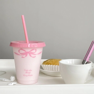 Roze herbruikbare beker met rietje en strikpatroon in gezellige middagthee omgeving