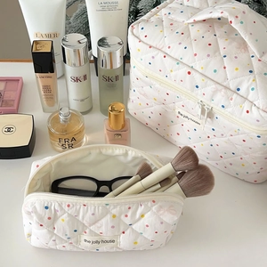 Detailed view of polka dot quilted cosmetic bag set with zipper and handle on a vanity