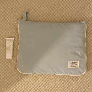 Detail of light blue waterproof travel organizer bag with handle on textured carpet
