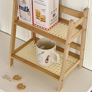 Detail view of double-layer cream rattan desktop organizer with items on wooden shelves