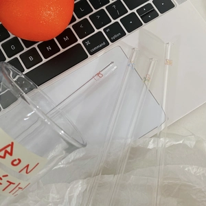 Eco-friendly glass straw set with cute butterfly and tulip prints on a laptop desk