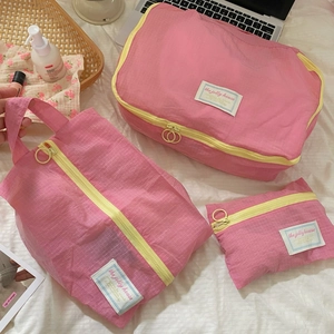 Pink checkered travel organizers set with yellow zippers on a clean white bed