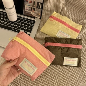Three colorful nylon travel organizer pouches on a cozy waffle blanket background