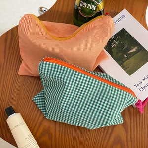 Close-up of checkerboard makeup bags with vibrant contrast zippers on a wooden table