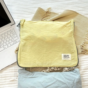 Detail of a light yellow nylon travel storage bag with zipper and brand label on bedding