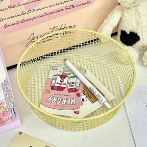 Top view of a pale yellow metal wire mesh desk basket with stationery and cute accessories