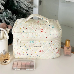 Detail of beige quilted makeup bag with colorful polka dots and bow patterns