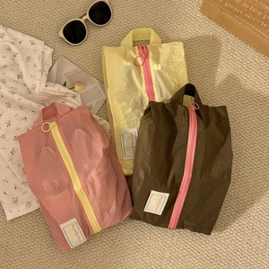 Detailed view of portable travel shoe bags in pink, yellow and brown with sturdy handles