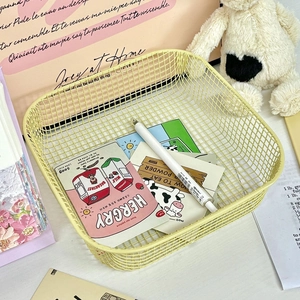 Detail of light yellow iron wire storage basket with office stationery and decorations