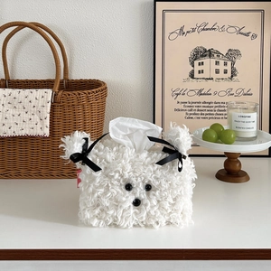 Close-up of fluffy white dog-shaped tissue box cover with cute black bows in cozy setting