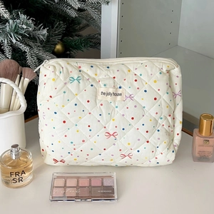 Detail of white quilted cosmetic bag with colorful polka dots and bow patterns