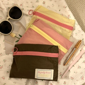 Three colorful checkered travel organizers with large ring zippers on floral fabric