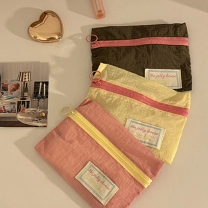 Detailed view of three-piece nylon travel organizers with zippers in pink yellow and brown