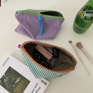 Detail view of large checkered toiletry bags with contrasting zippers and woven pulls
