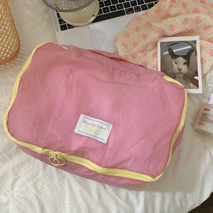 Close-up of pink nylon travel organizer with yellow zipper and textured grid fabric