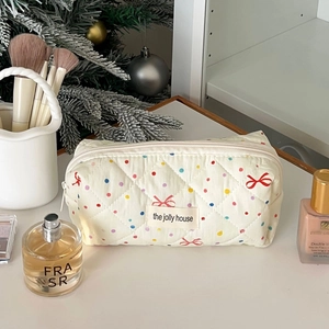 Detailed view of quilted makeup bag featuring colorful dots and festive red bow motifs