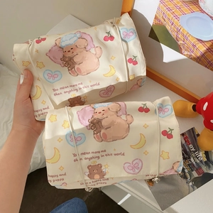 Close-up of a roll-up bear pattern toiletry bag with beige fabric and ribbon tie