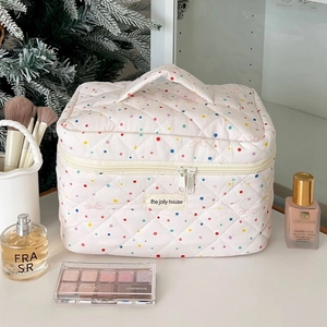Detailed view of quilted white cosmetic bag with colorful polka dots and double zipper