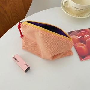Macro shot of orange checkered cosmetic bag with purple lining and red rope zipper pull