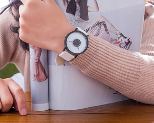 Minimalist quartz watch with white leather strap and creative black dial on a model wrist